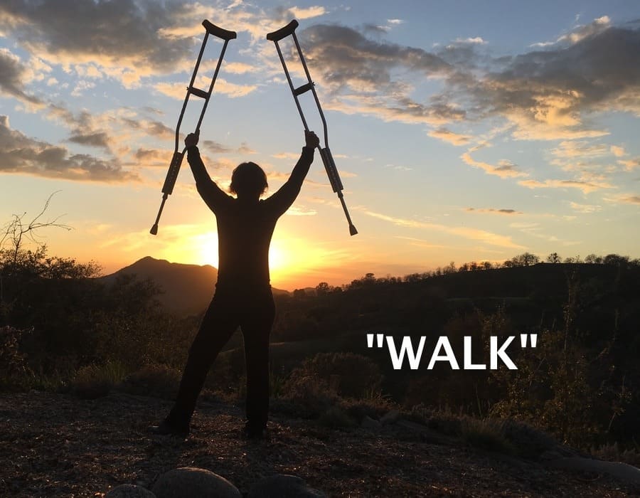 Amanda holding crutches up into the sky, at sunset