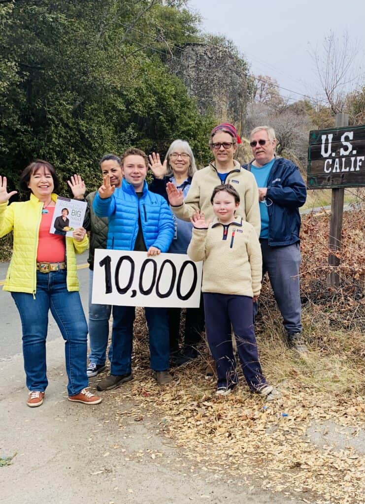 Amanda Rose and the team that helped her ship 10,000 books, holding a sign that says "10,000)