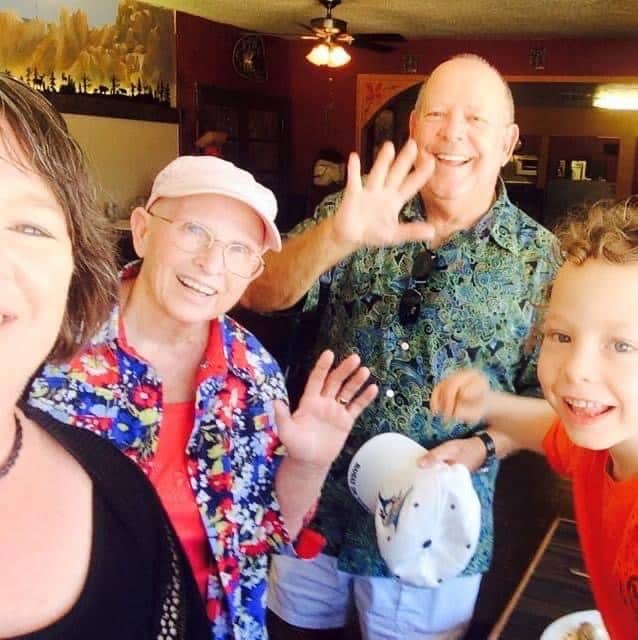 Amanda, son Alastair, Aunt Kathy, and Uncle Fred, waving in a selfie-style photo