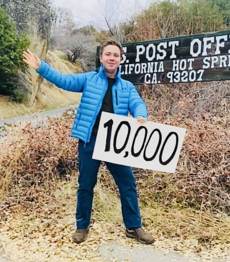 Amanda's son Frederick holding a sign that says "10,000"