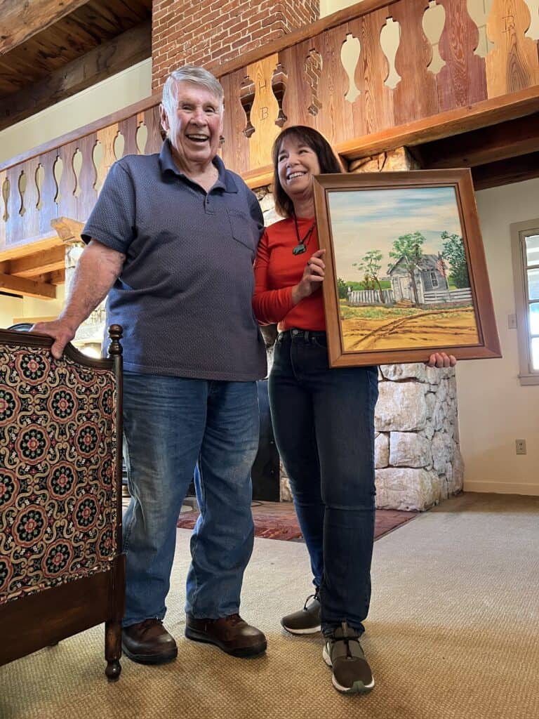 Amanda and her dad hold the painting in her living room