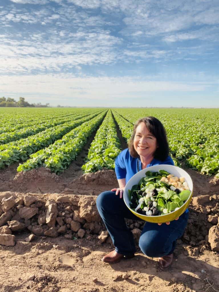 Amanda Rose in a field of romaine holding a Ridiculously Big Salad